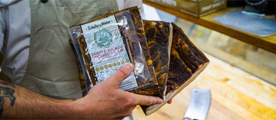 Butcher holding Double Smoked Uncured Bacon retail package