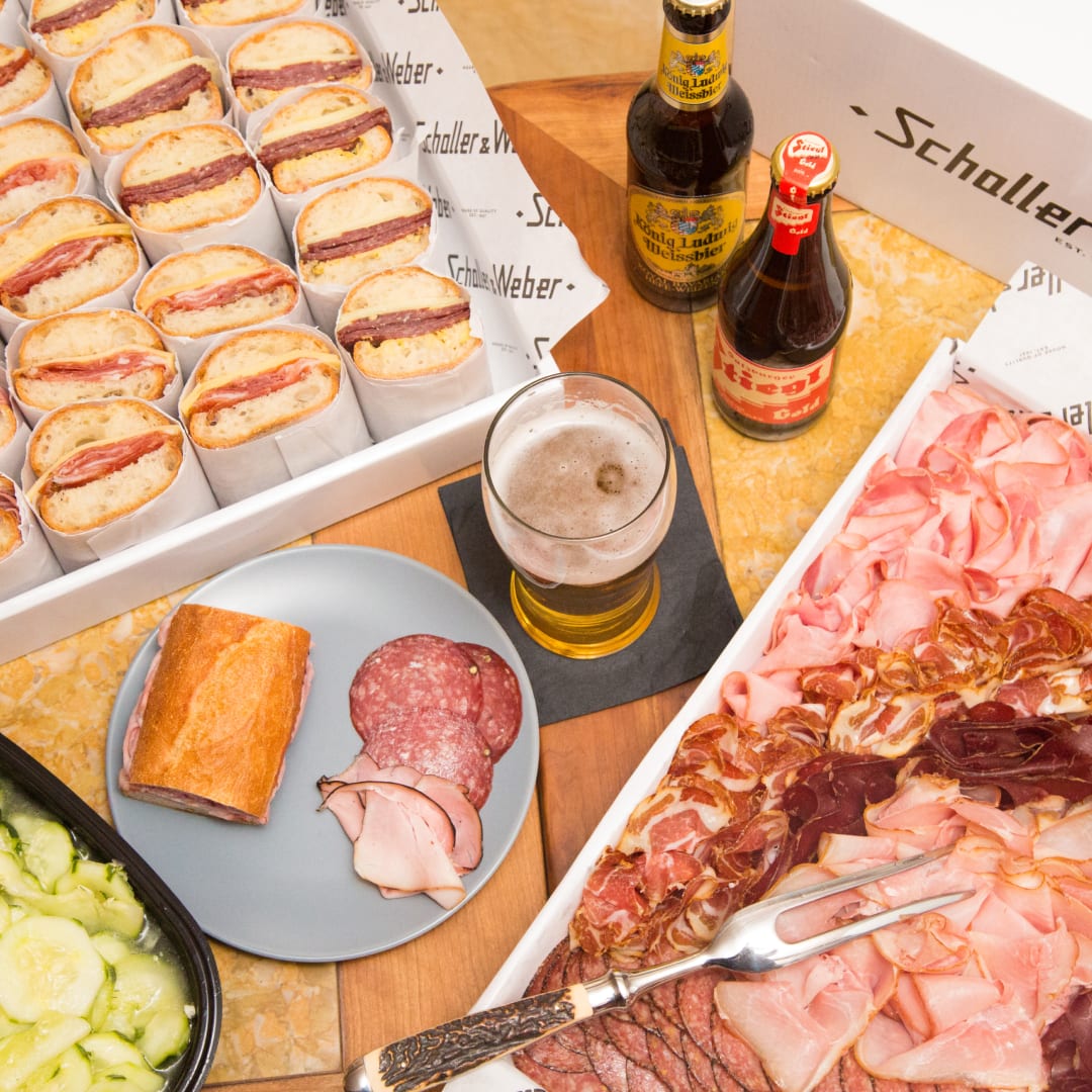 Catering spread of cold cut meats, sandwiches, pickles, and imported beers